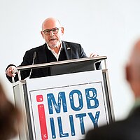 Verkehrsminister Winfried Hermann spricht auf dem Podium der i-Mobility.