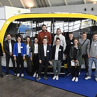 Ein autonomer Shuttle-Bus aus dem Forschungsprojekt RABus auf der i-Mobility mit Menschen davor.