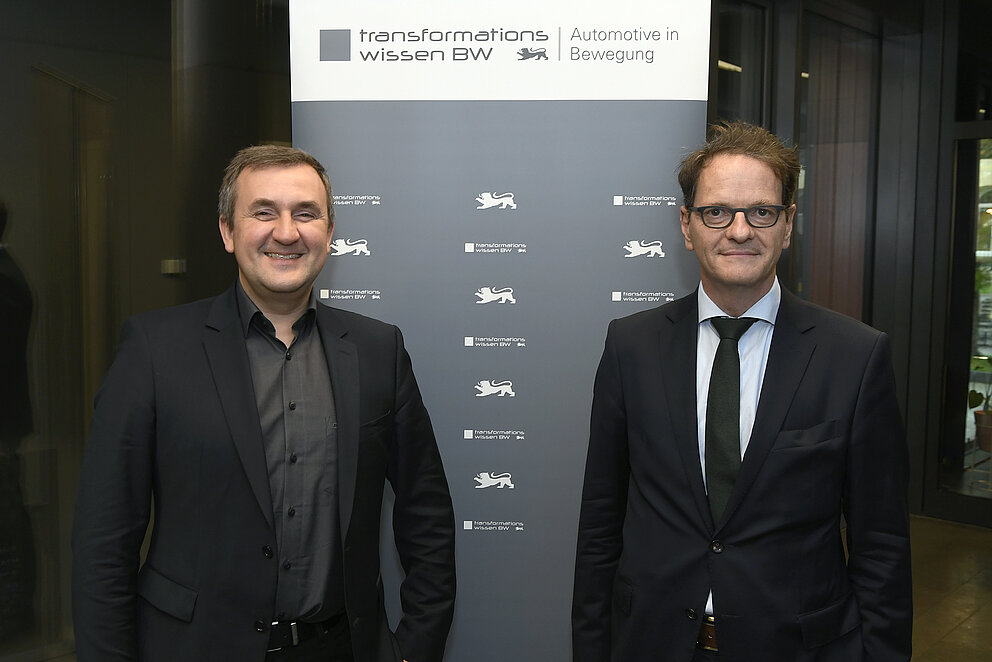 Dr. Wolfgang Fischer, e-mobil BW und Michael Kleiner, Ministerium für Wirtschaft, Arbeit und Tourismus Baden-Württemberg blicken lächelnd in die Kamera.