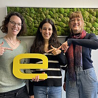 Caroline Geltz, Marie-Claire Landenberger und Stephanie Wagner halten ein gelbes "e" und zeigen darauf. 