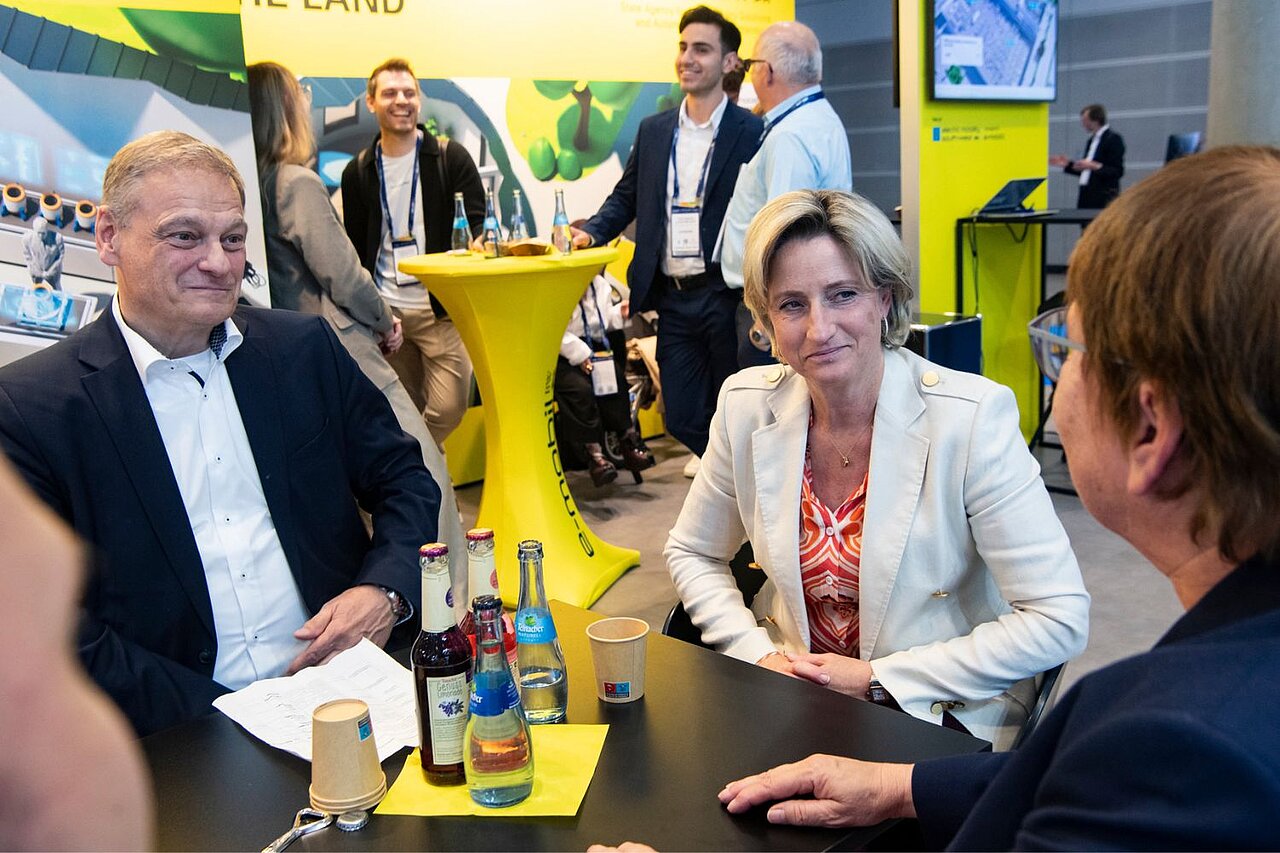 Eine Frau und ein Mann sitzen an einem Tisch und unterhalten sich mit zwei weiteren Personen.