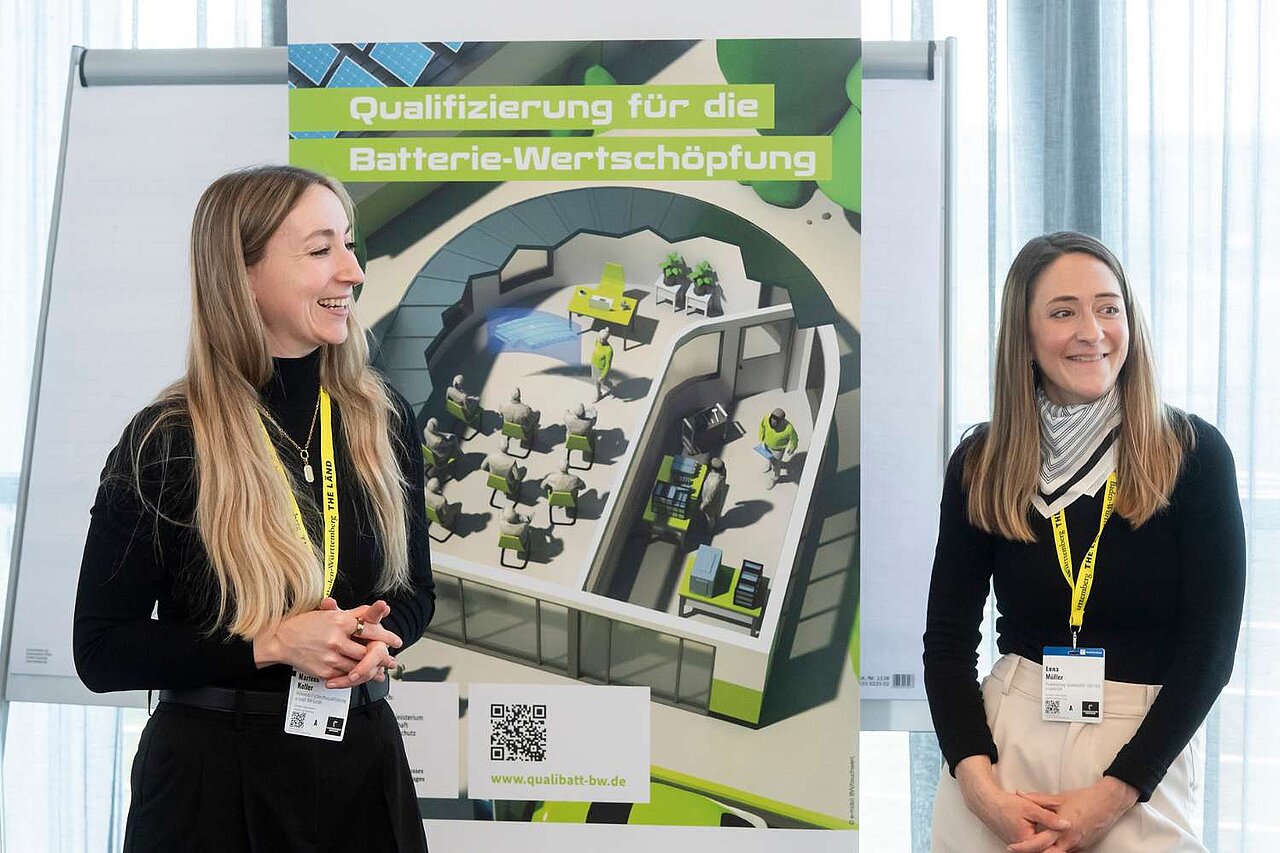 Marleen Keller und Lena Müller vor einem QualiBatt BW Poster. Sie lachen.