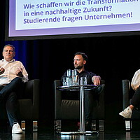 Drei Personen diskutieren gemeinsam auf einem Podium.