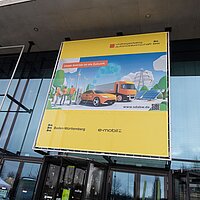 Eine Außenaufnahme von einer Leinwand der SDA-Jahresveranstaltung vor der Messehalle West der Landesmesse Stuttgart. 