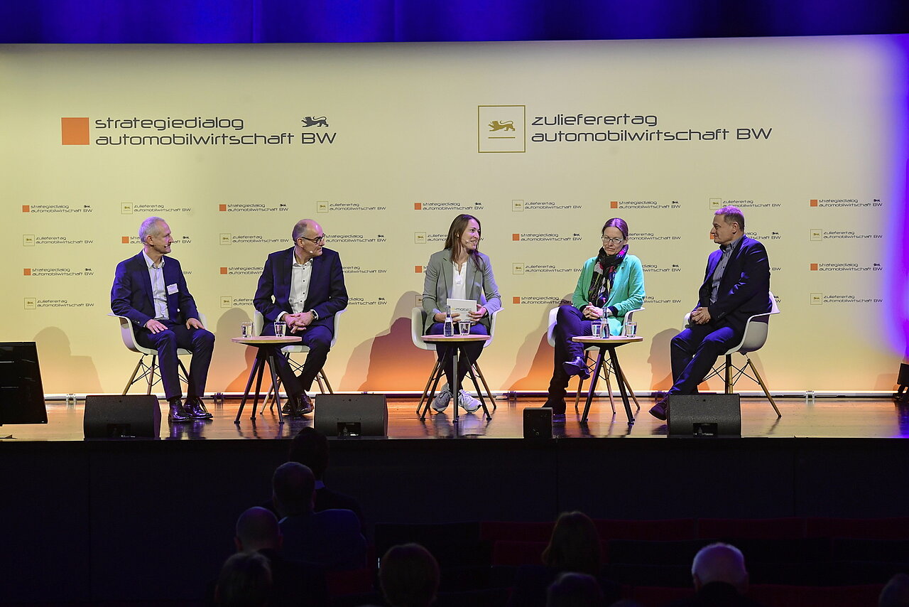 Fünf Personen sitzen auf dem Podium zu einer Diskussionsrunde. 