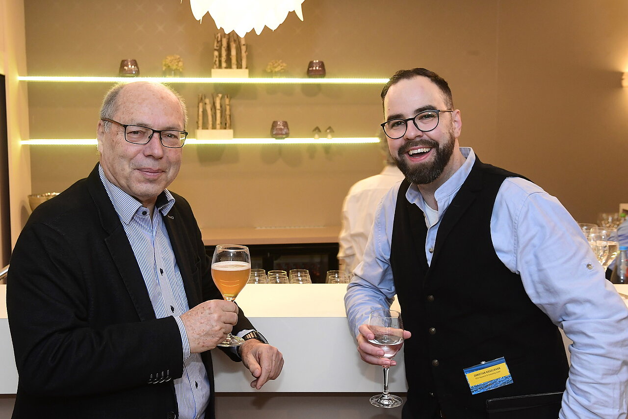 Gäste der Veranstaltung "e-mobil BW connects" unterhalten sich und trinken etwas.