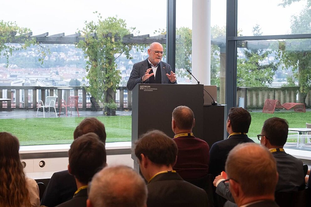 Verkehrsminister Winfried Hermann steht auf dem Podium und hält eine Eröffnungsrede bei einer Veranstaltung.
