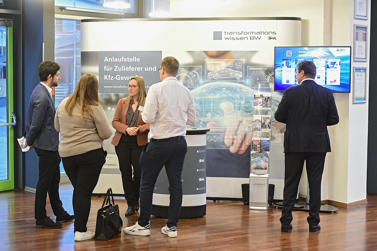 Vier Personen besuchen den Stand der Landeslotsenstelle Transformationswissen BW.