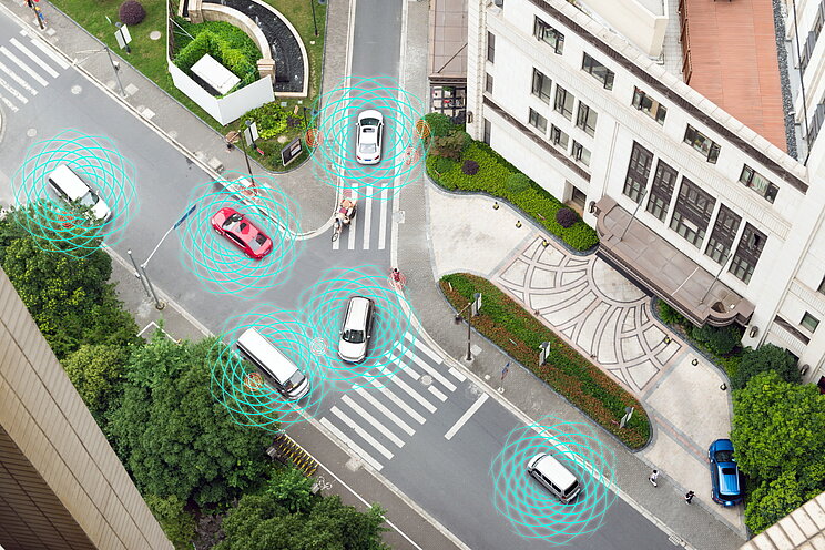 Grafische Darstellung mit Blick von oben auf eine Kreuzung mit autonom fahrenden Fahrzeugen. 