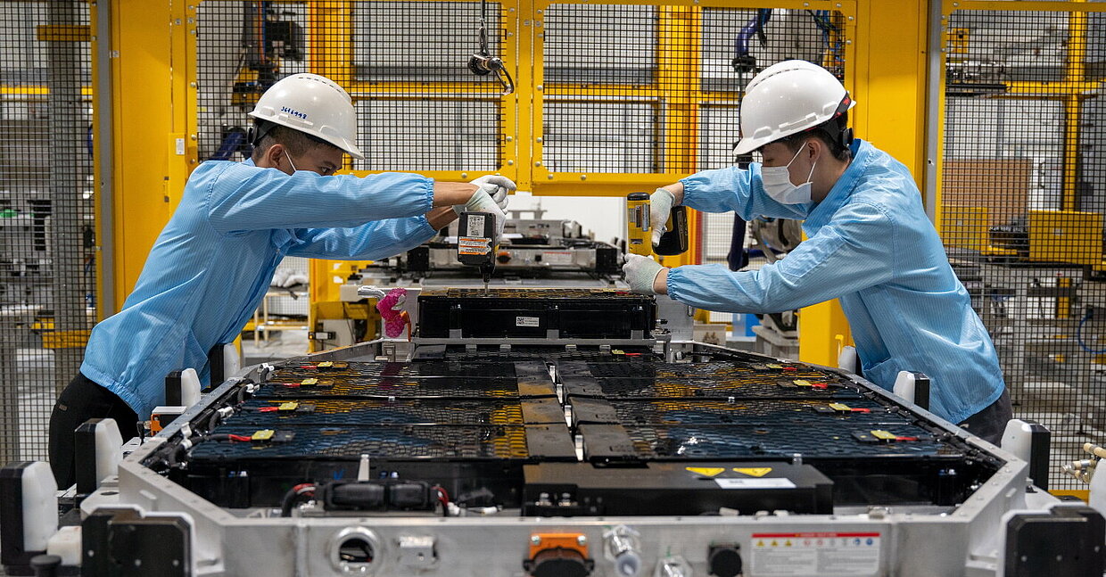 Two people working in a factory on a battery for electric vehicles.