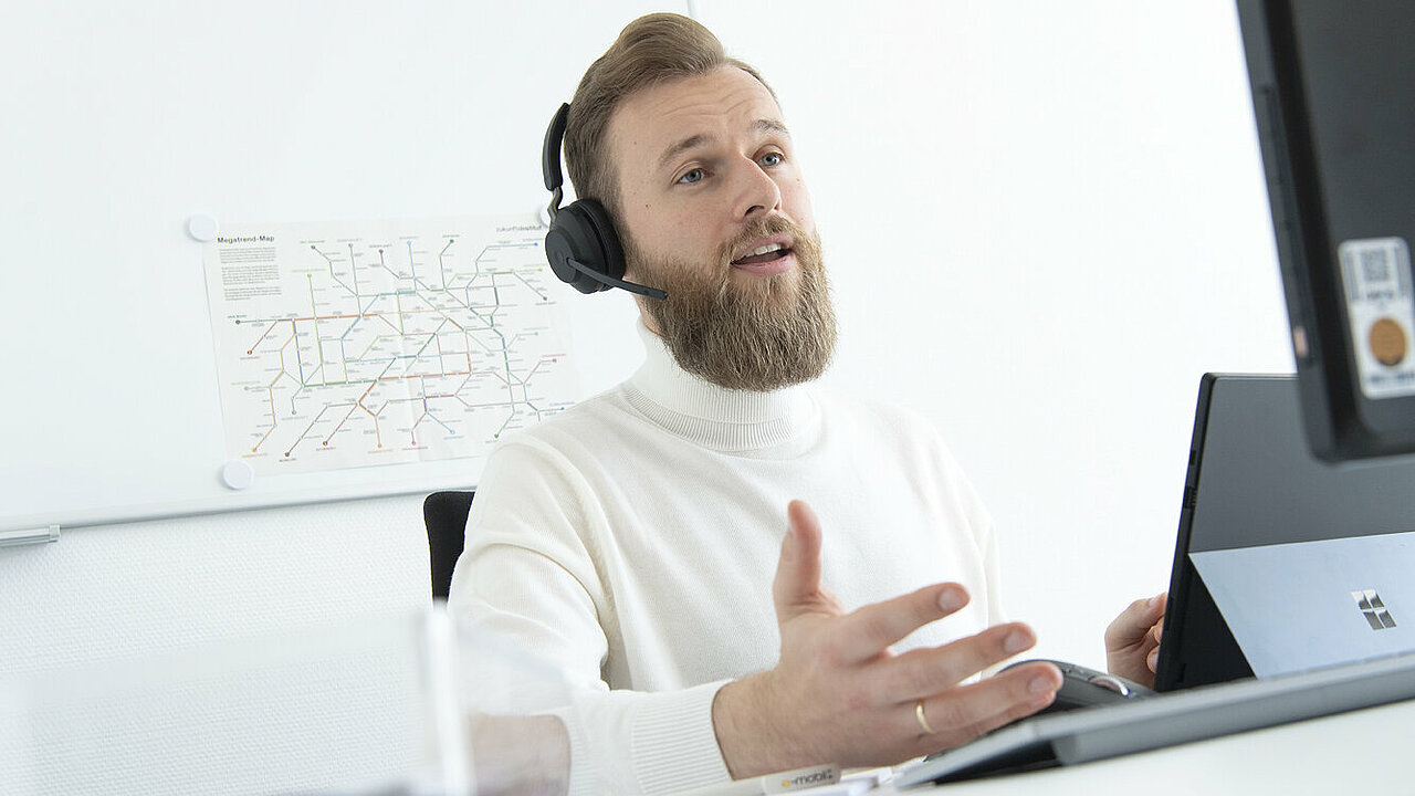 Ein Mann mit Headset sitzt vor dem Computer und spricht. 