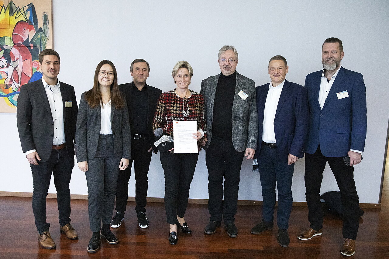Die baden-württembergische Wirtschaftsministerin Dr. Nicole Hoffmeister-Kraut besucht den Zulieferertag Automobilwirtschaft BW 2022. Es ist ein Gruppenfoto gemeinsam mit den internationalen Gästen zu sehen..