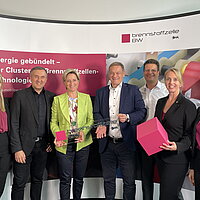 Das Team des Clusters Brennstoffzelle BW und Wirtschaftsministerin Dr. Nicole Hoffmeister-Kraut posieren vor einem großen Aufsteller