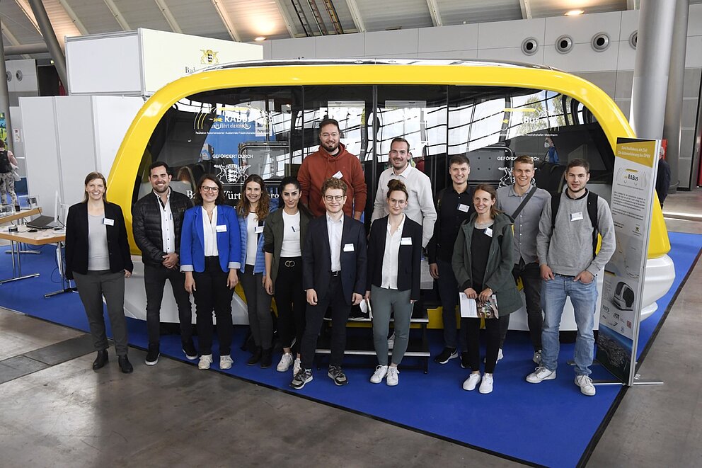 Ein autonomer Shuttle-Bus aus dem Forschungsprojekt RABus auf der i-Mobility mit Menschen davor.