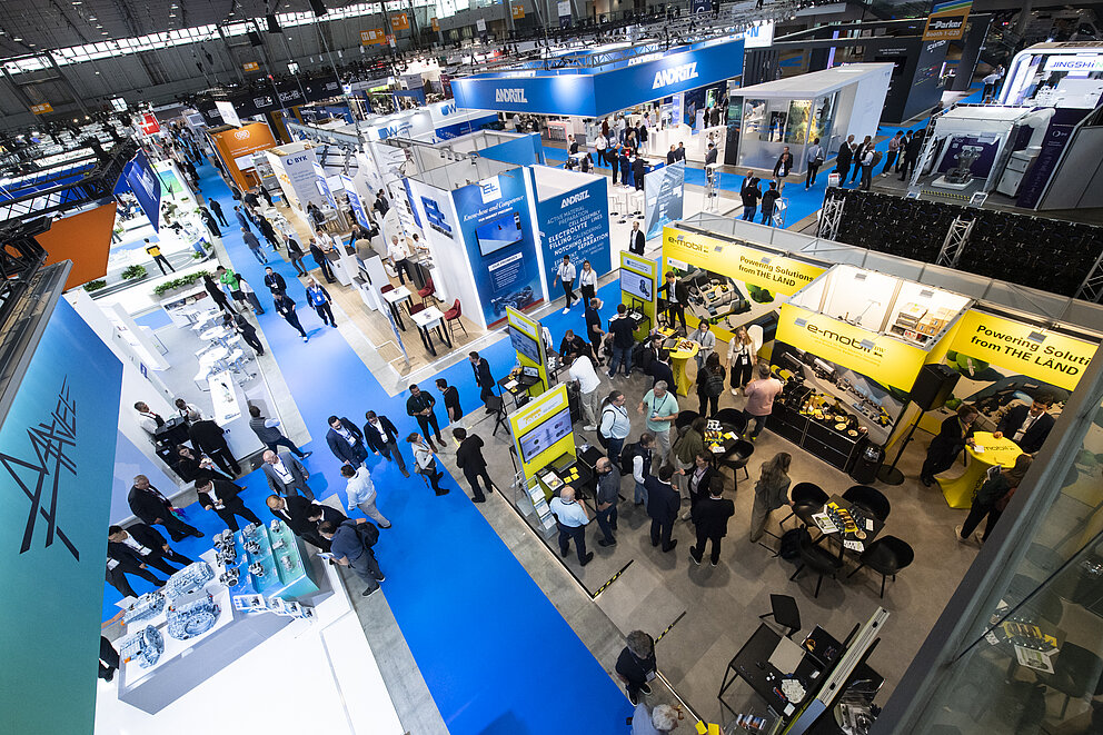 Von oben: Blick in die Messehalle mit blauen und gelben Messeständen.