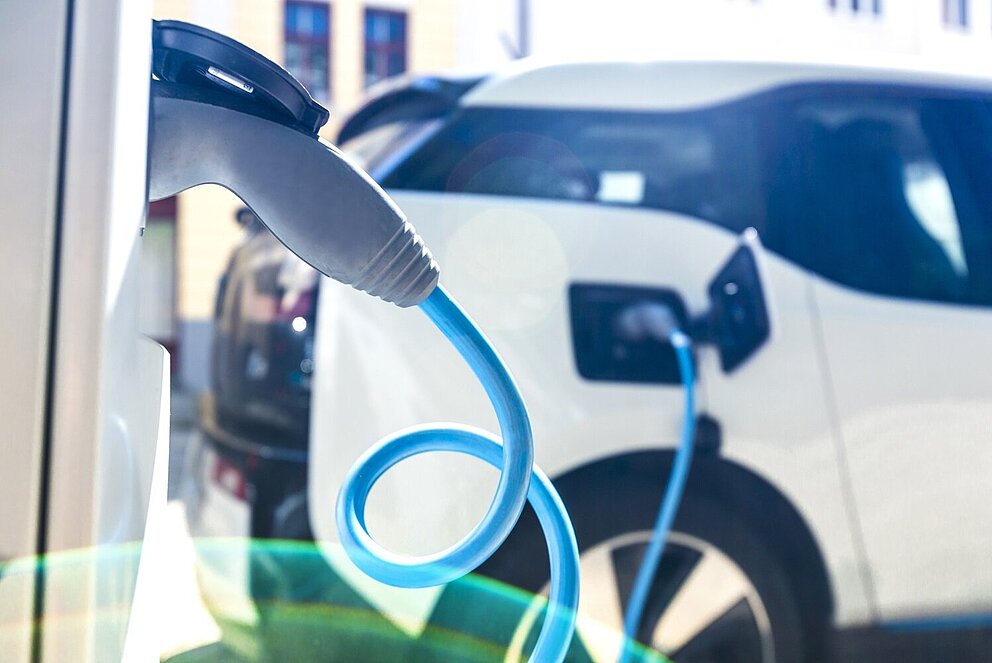 Ein weißes Elektroauto lädt den Akku an einer Ladesäule auf.