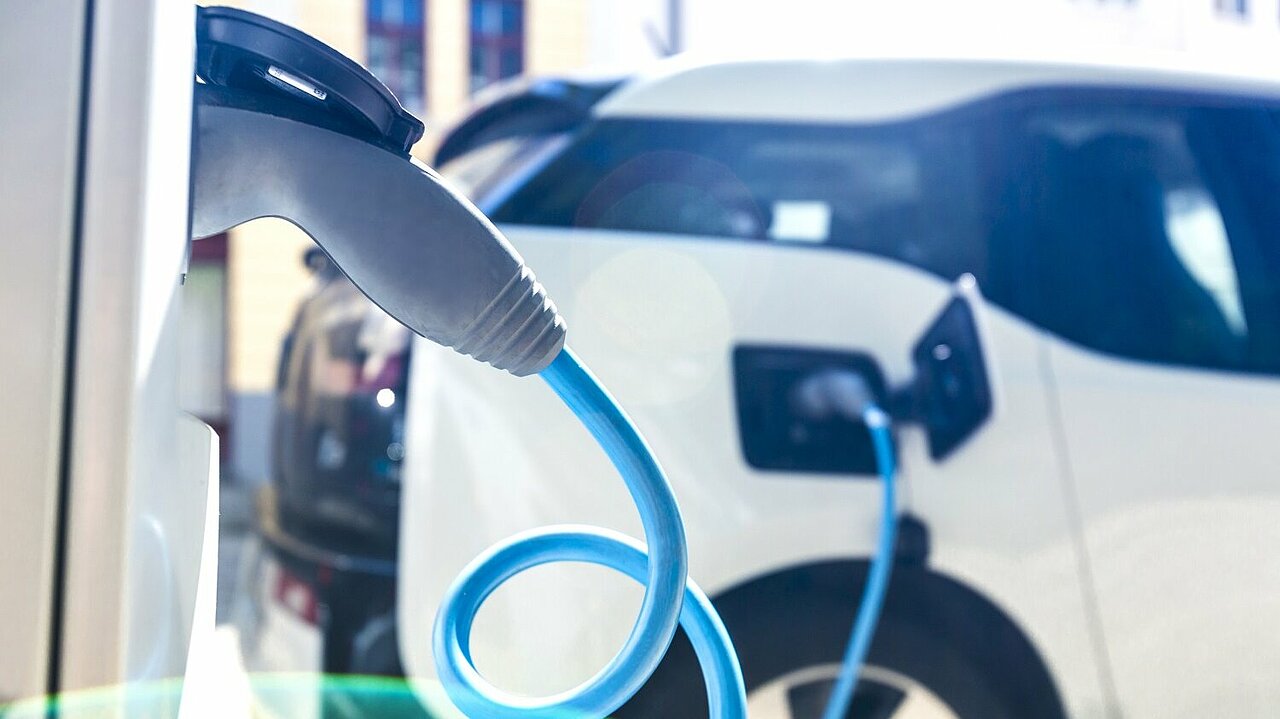Ein weißes Elektroauto lädt den Akku an einer Ladesäule auf.