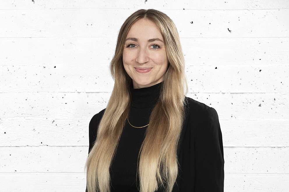 Portrait einer lächelnden Frau mit blondem Haar und schwarzem Blazer