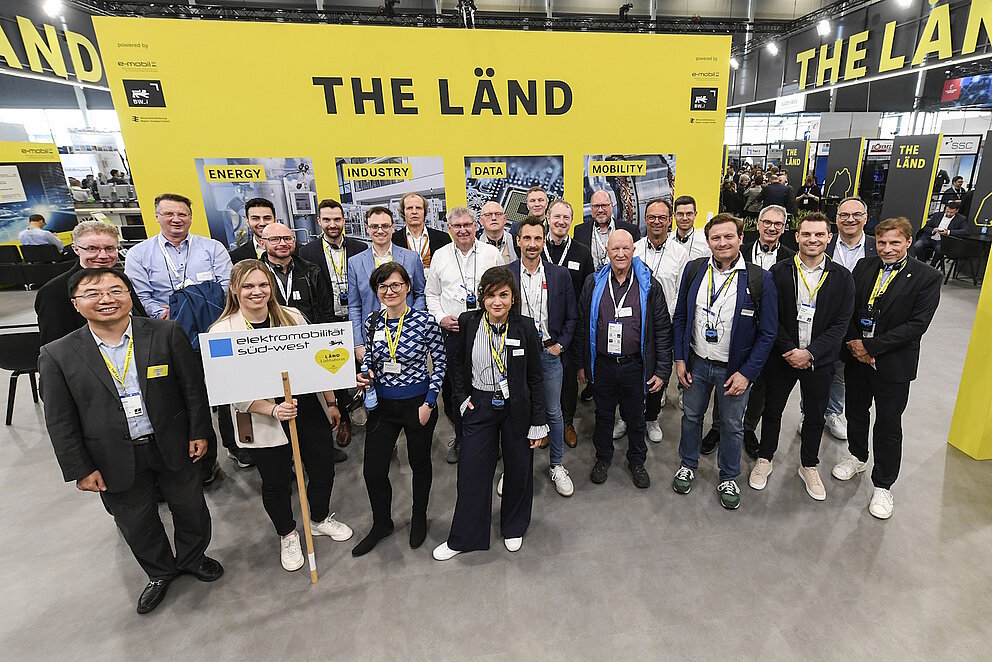 Eine Gruppe von ca. 30 Personen auf einem Messestand von der Marke "THE LÄND".