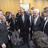 Bundeskanzler Friedrich Merz mit Ministerpräsident Winfried Kretschmann und Ola Källenius mit anderen Teilnehmern des Strategiedialog Automobilwirtschaft in Stuttgart stehen im Kreis zusammen.