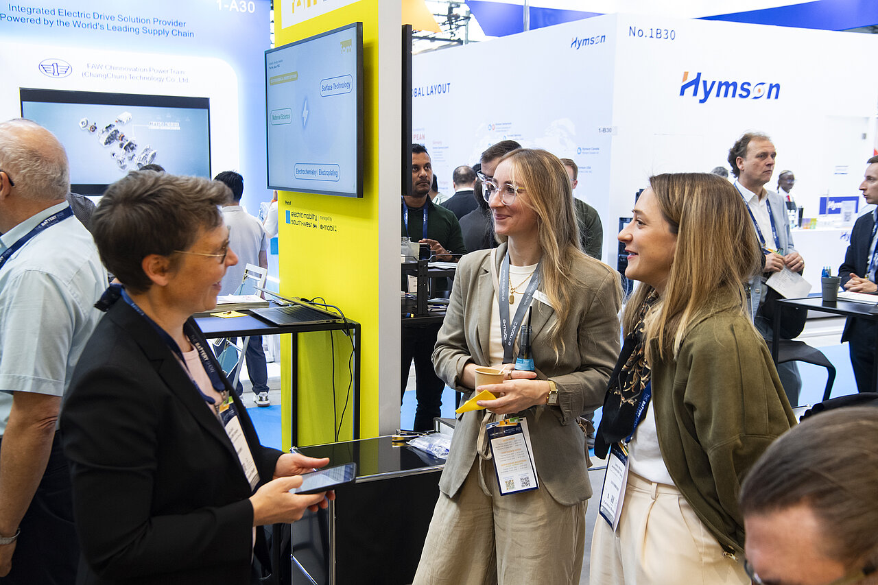Drei Frauen unterhalten sich auf einem Messestand.