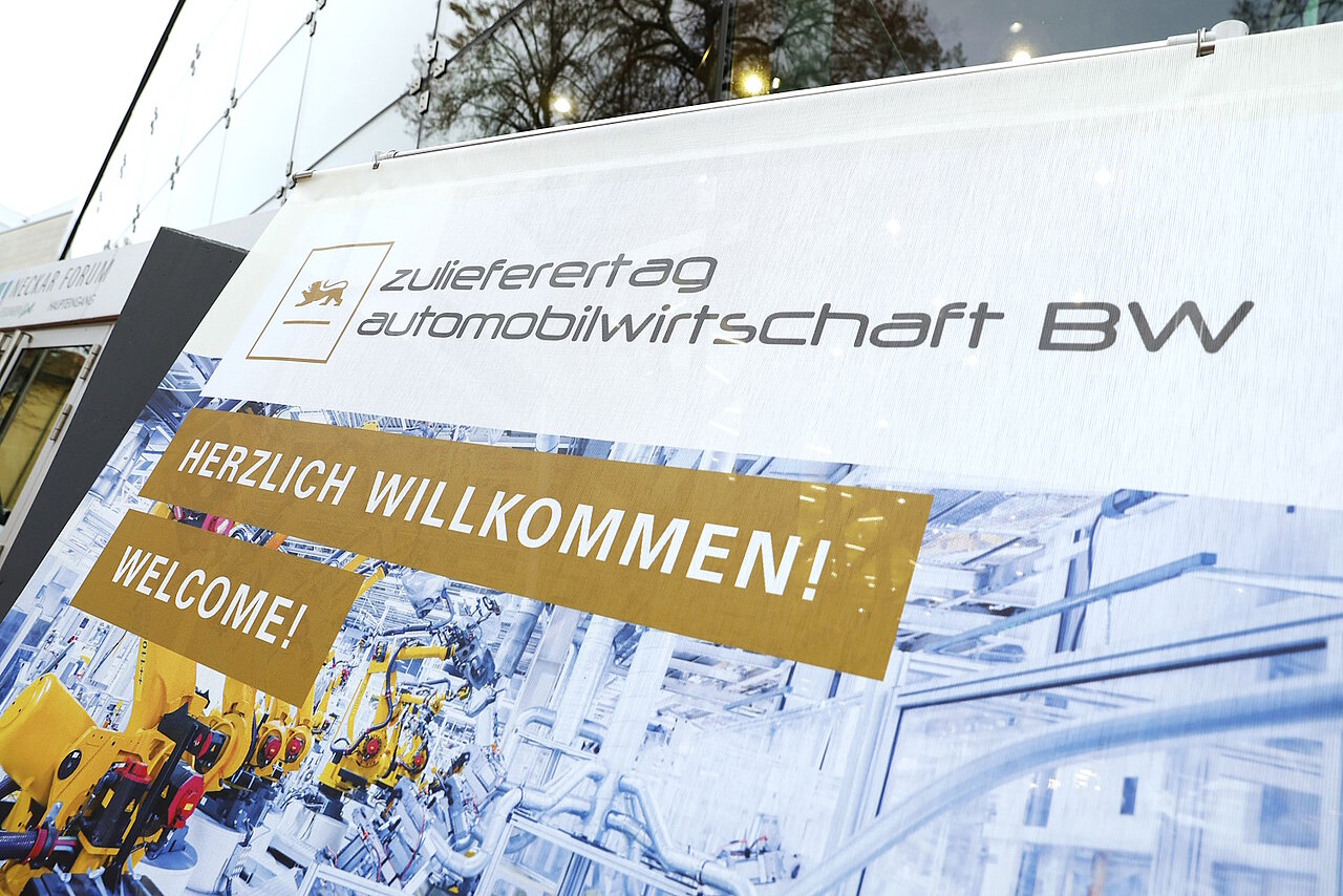 Detailsaufnahme des Plakates vor dem Neckar Forum Esslingen. Darauf steht Willkommen und Welcome auf dem Zulieferertag Automobilwirtschaft BW 2022!
