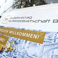 Detailsaufnahme des Plakates vor dem Neckar Forum Esslingen. Darauf steht Willkommen und Welcome auf dem Zulieferertag Automobilwirtschaft BW 2022!