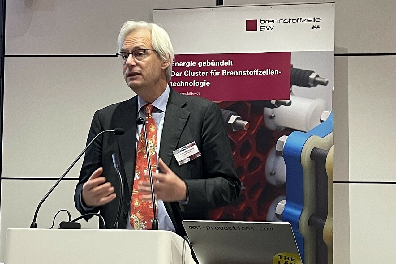 Prof. Dr. Thomas Heimer, Hochschule RheinMain steht vor einem Rednerpult bei der 10 Jahresveranstaltung des Clusters Brennstoffzelle BW