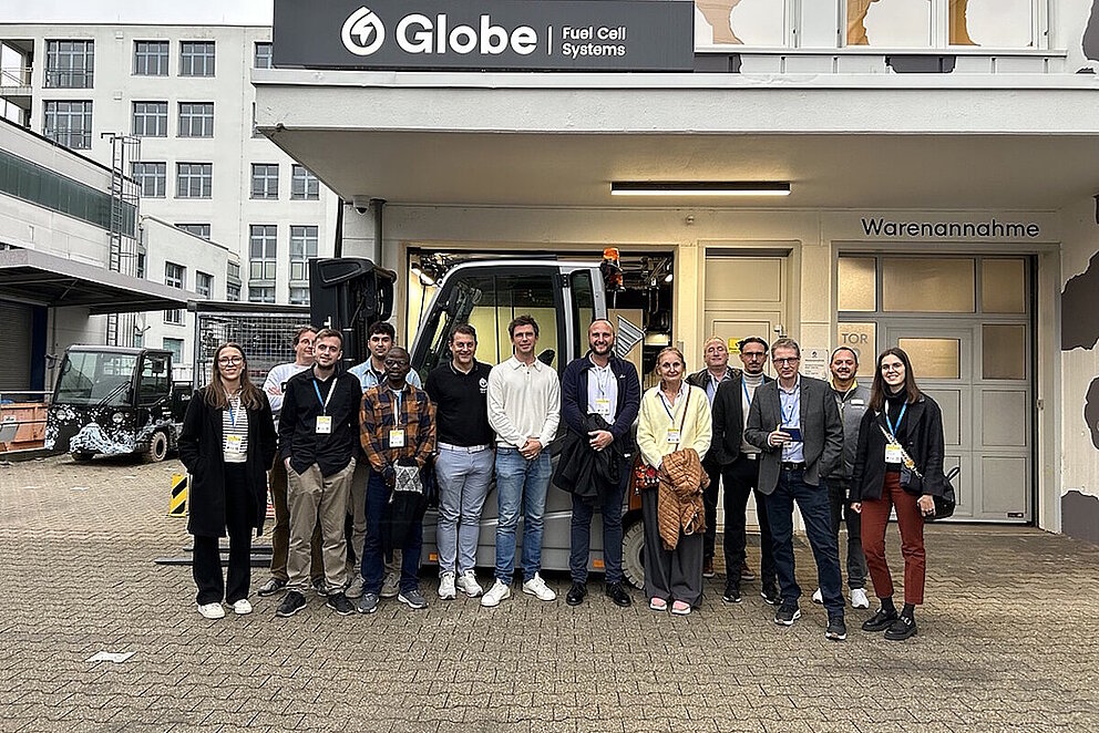 Teilnehmer der Führung stehen vor einer Halle von Globe Fuel Cell Systems