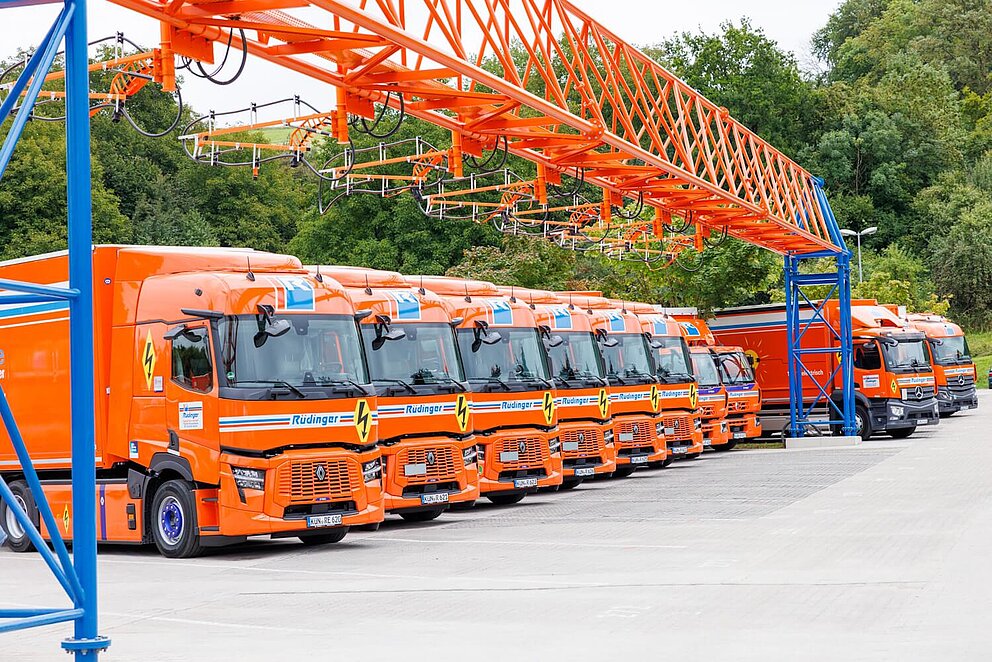 E-Lkw-Ladepark mit Overhead-Ladeinfrastruktur, an der sieben Ladepunkte montiert sind.