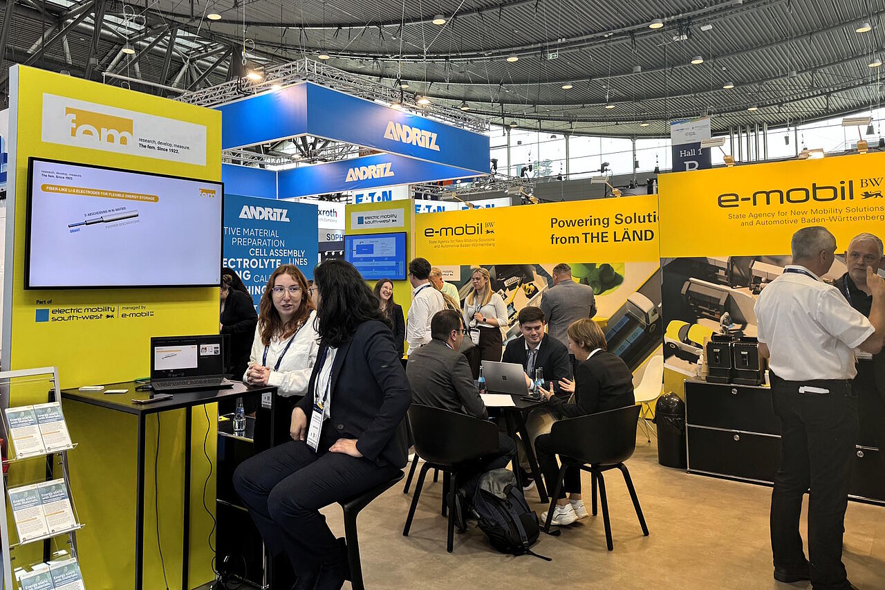 Mehrere Personen tauschen sich auf einem Messestand im Stehen und Sitzen aus.