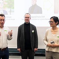 Drei Speaker:innen bei einer Veranstaltung, die zum Publikum sprechen.