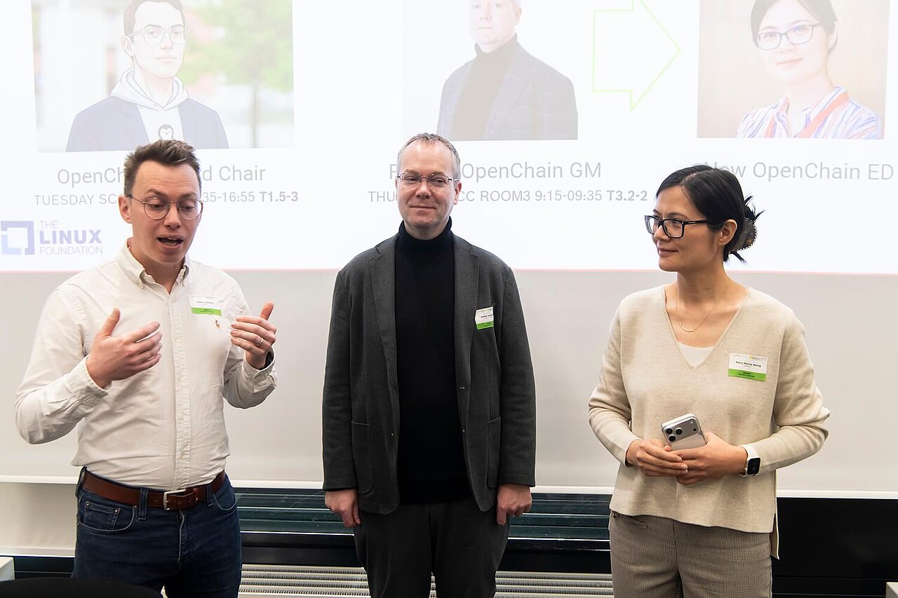 Drei Speaker:innen bei einer Veranstaltung, die zum Publikum sprechen.