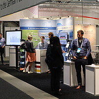 Visitors talking with exhibitors at the German pavilion at the EVS35 in Norway.