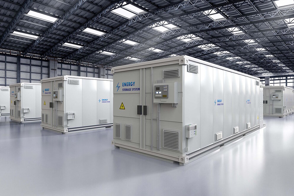 Mehrere Reihen weißer Batteriespeichercontainer stehen in einer hell erleuchteten Halle.