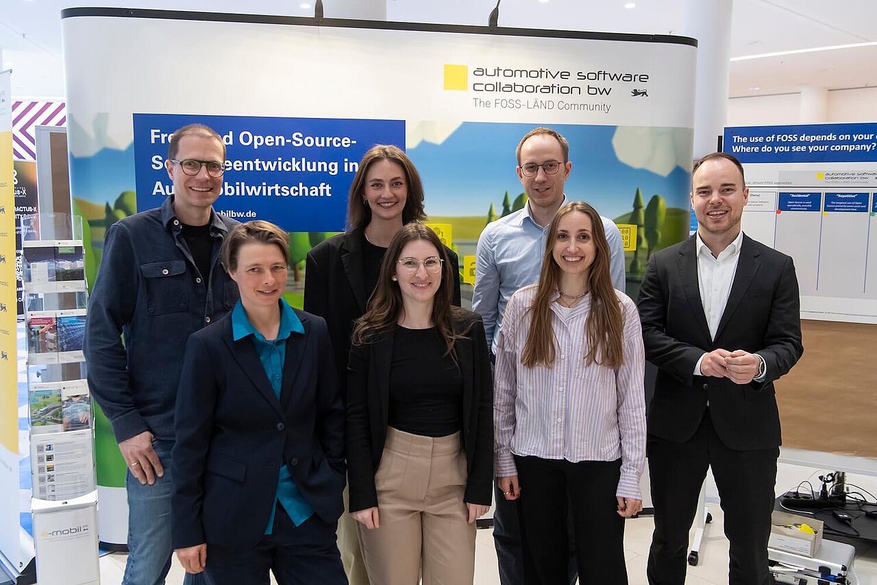 Ein Teil des Teams der e-mobil BW GmbH bei der OpenChain and Friends 2026. Das Team posiert vor einer Messewand.