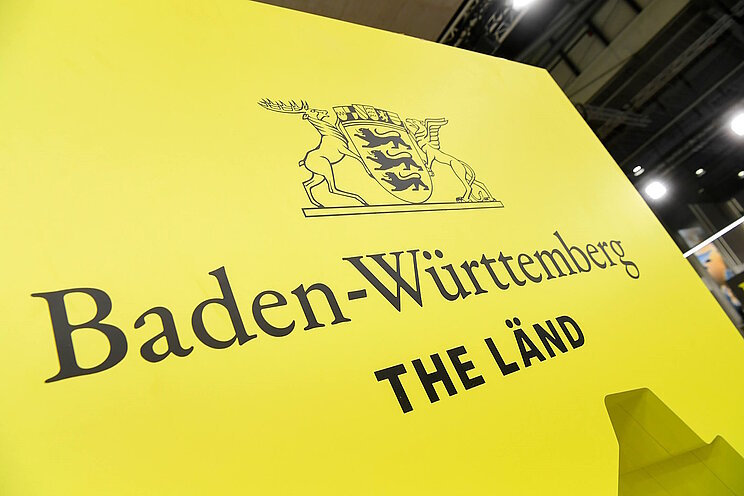 Das Logo von Baden-Württemberg mit dem Slogan "THE LÄND" auf einer Wand des Messestandes von Baden-Württemberg.
