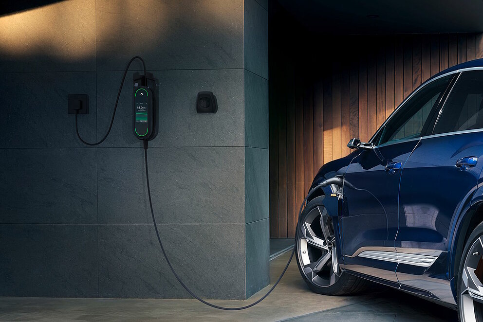 Ein blaues E-Auto steht in einer Garage und wird über eine Wallbox aufgeladen