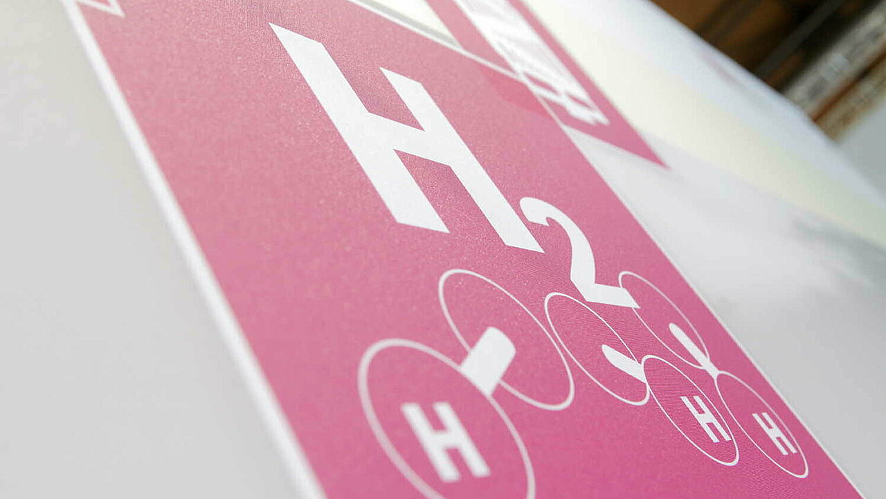Piktogramm "H2" für Wasserstoff auf rotem Grund an einer Messewand