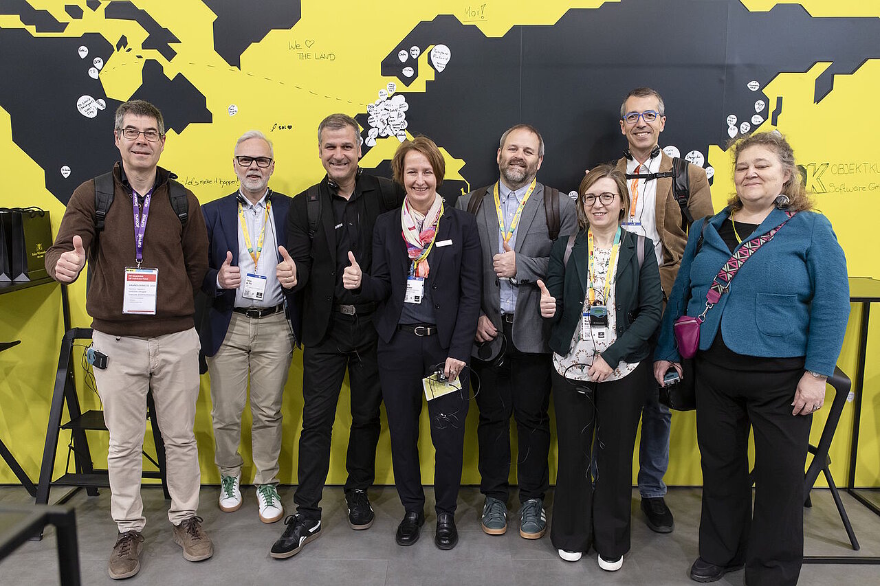 8 Personen stehen vor einer gelben Weltkarte