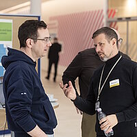 Zwei Teilnehmende bei der OpenChain and Friends Veranstaltung im Gespräch.