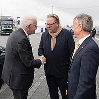 Der Ministerpräsident Winfried Kretschmann bei einer Begrüßung mit zwei weiteren Personen. 