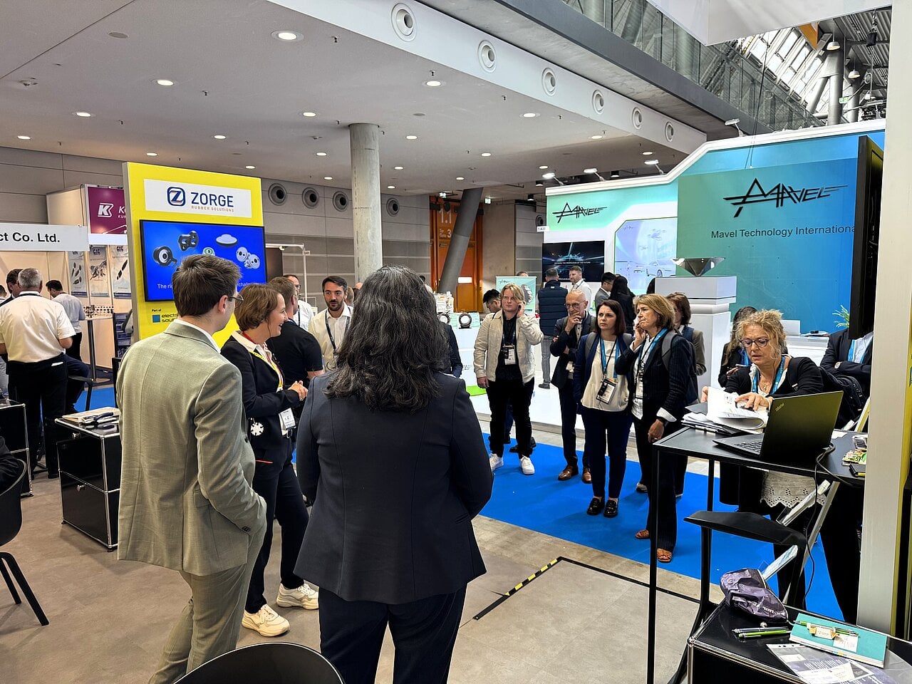 Eine Gruppe Personen informiert sich auf einem Messestand und hört über Kopfhörer einer Führung zu.