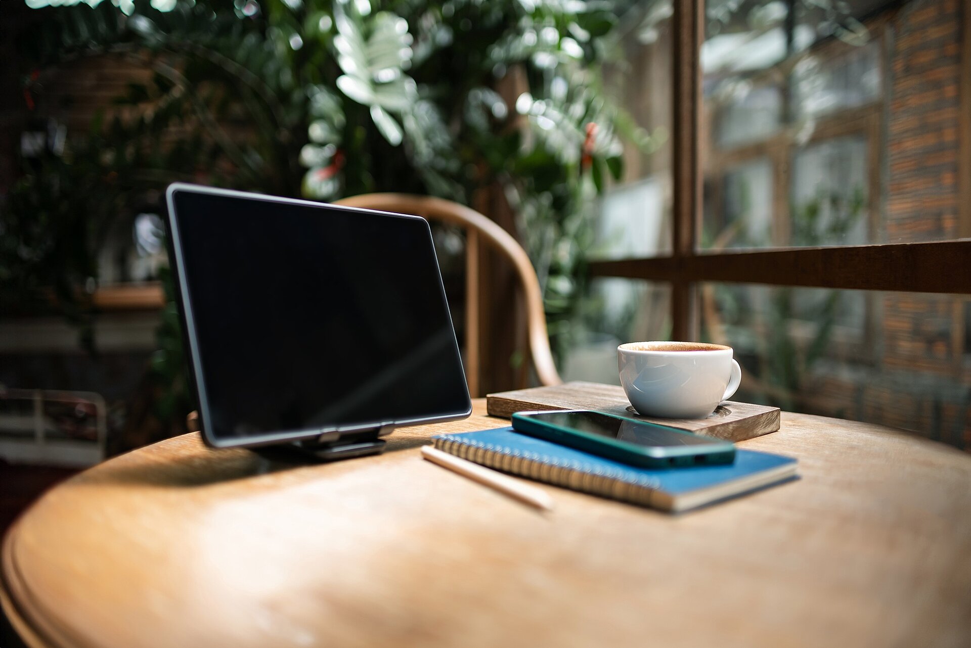 Arbeitsplatz Auf einem runden Tisch stehen ein Bildschirm, mehrere Bücher und eine Kaffeetasse.