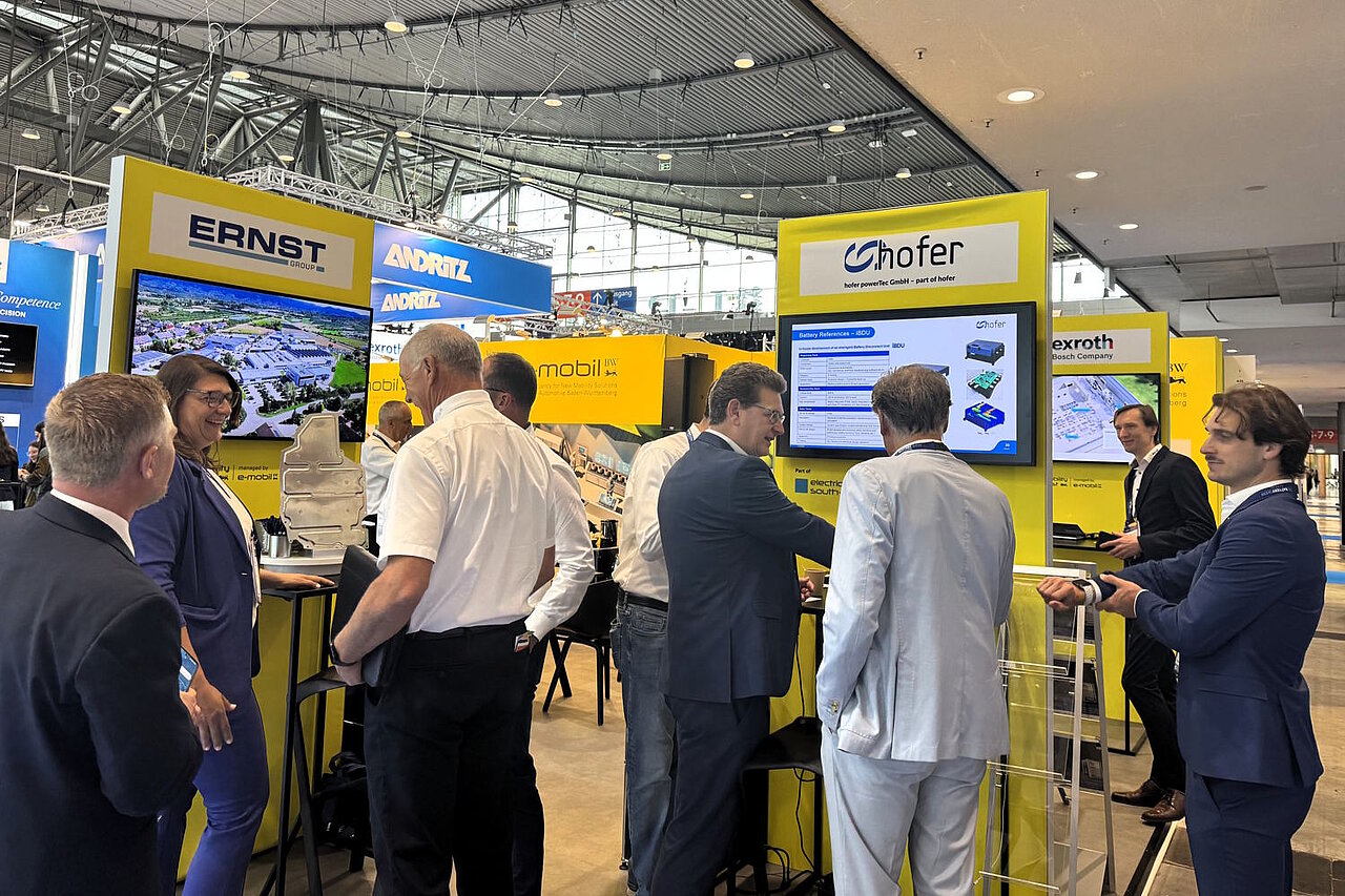 Mehrere Personen auf einem Messestand, die sich unterhalten und Exponate anschauen