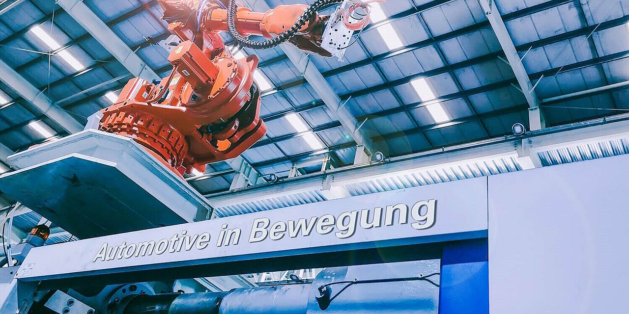 Roboterarm in der Produktion. Schriftzug "Automotive in Bewegung".