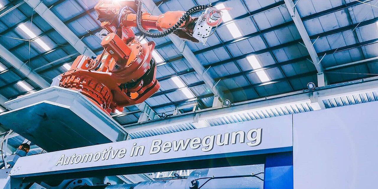 Roboterarm in der Produktion. Schriftzug "Automotive in Bewegung".