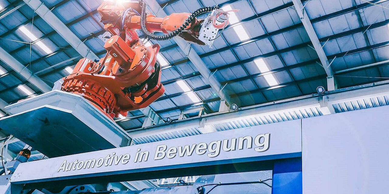 Roboterarm in der Produktion. Schriftzug "Automotive in Bewegung".