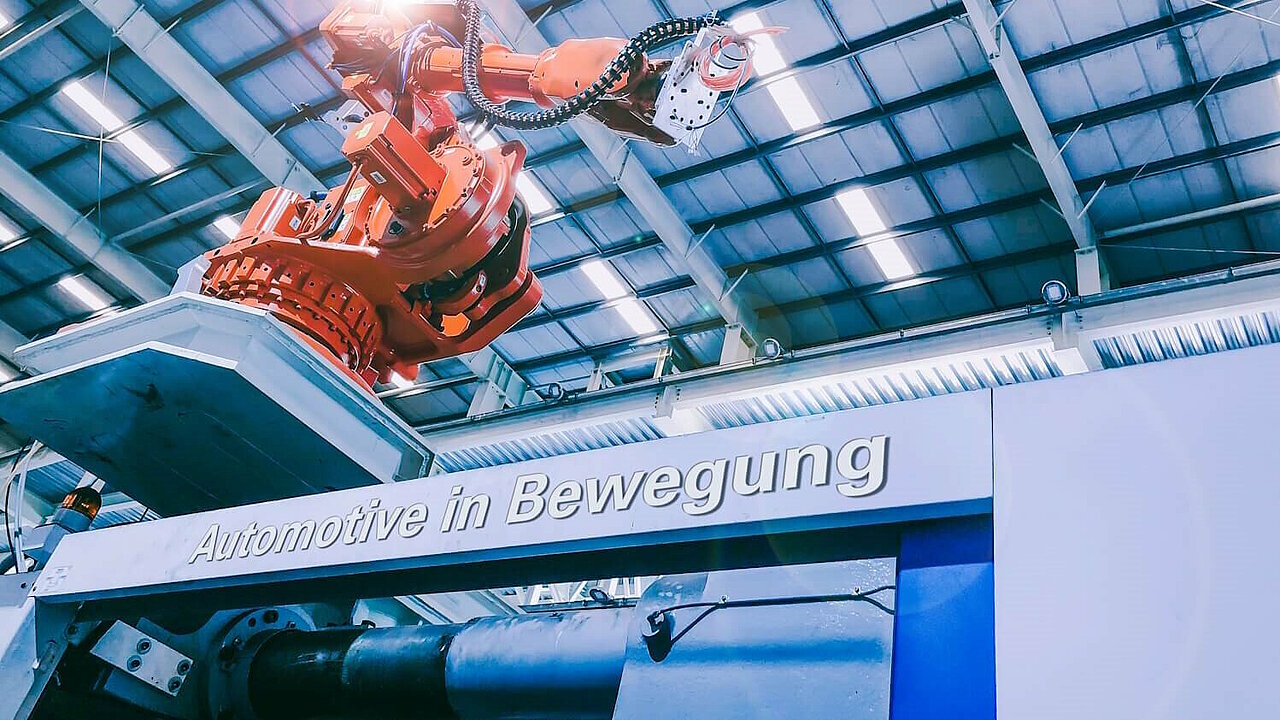 Roboterarm in der Produktion. Schriftzug "Automotive in Bewegung".