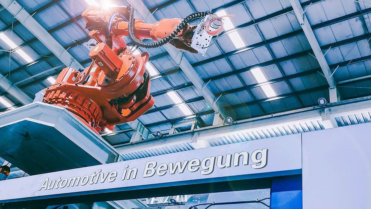 Roboterarm in der Produktion. Schriftzug "Automotive in Bewegung".